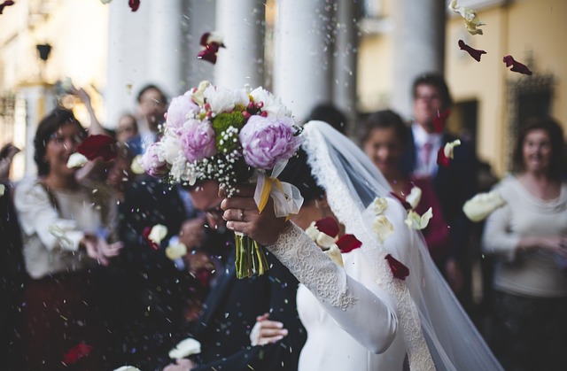 Brautpaar beim Auszug von den Gästen gefeiert und mit Blumen und Reis beworfen